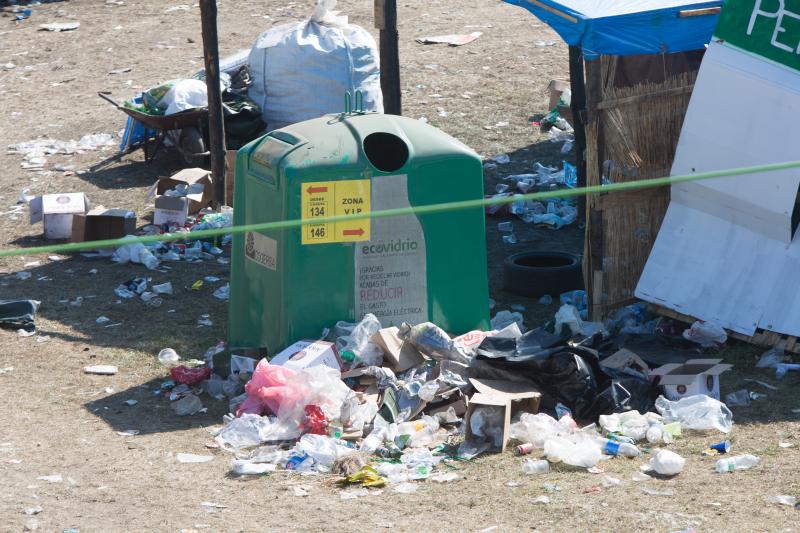 La multitudinaria fiesta del Xiringüelu ha dejado toneladas de basura en el prau Salcéu. Botellas, vasos, y restos de las coloridas casetas que son seña de identidad de la celebración han quedado esparcidos por el campo a la espera de que se retiren, unas labores que ya han comenzado.