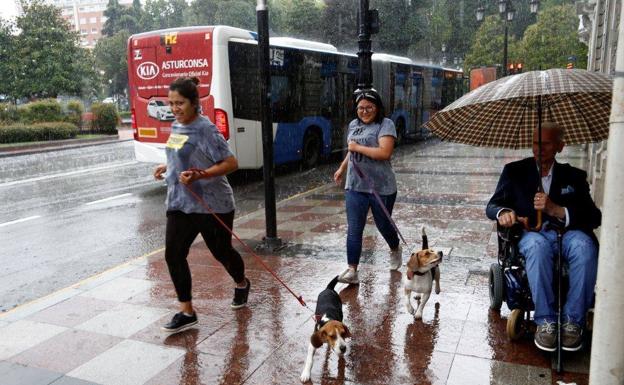 Galería. Dos mujeres corren bajo la tormenta en Oviedo.