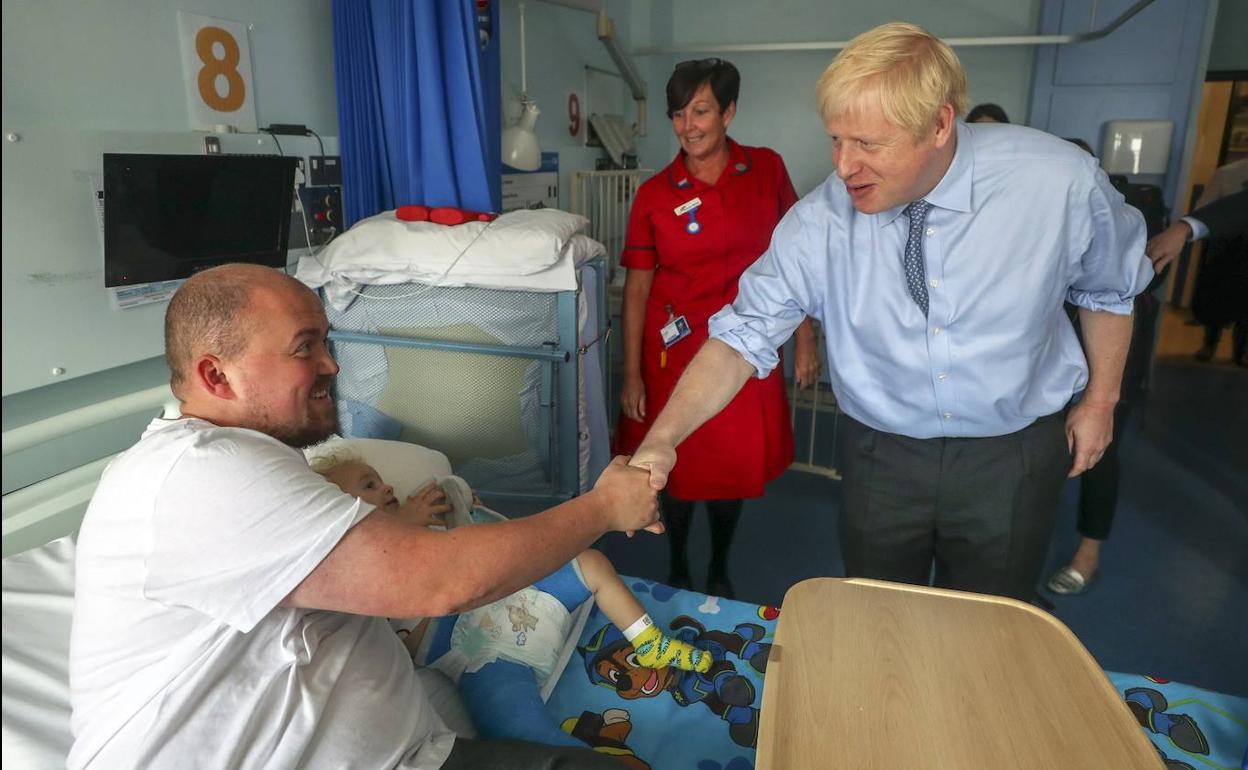 El 'premier' británico Boris Johnson saluda al padre de un niño ingresado en su visita al Royal Cornwall Hospital. 