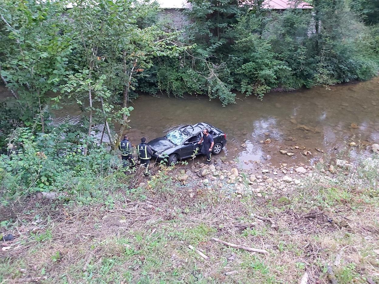 Bomberos junto al turismo que se precipitó al río en Infiesto. 