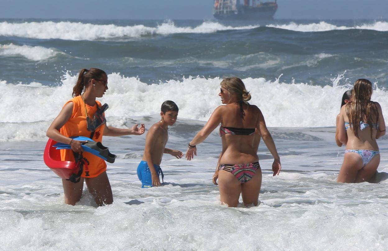 Una socorrista informa en Salinas de la prohibición del baño con bandera roja. 