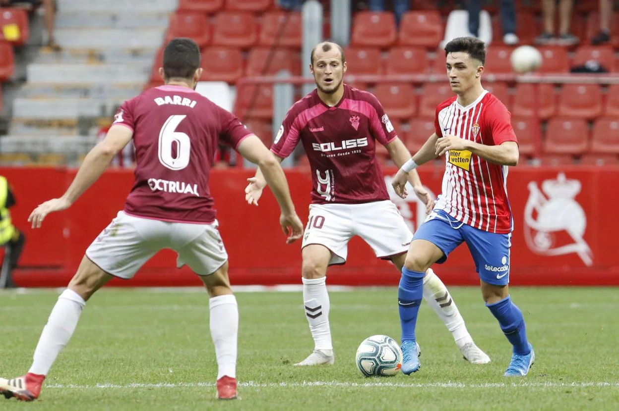 Manu García conduce un balón en la visita del Albacete a El Molinón, en la que marcó un gol, entre Roman Zozulia y Barri.