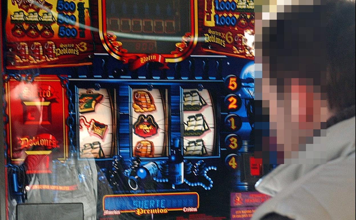 Un joven jugando en la tragaperras de una cafetería. 