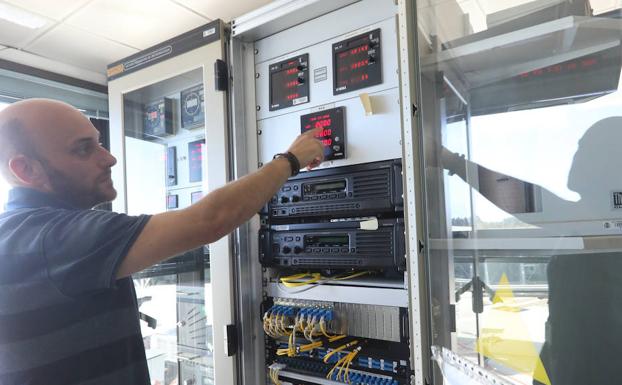 El jefe de la Oficina Meteorológica del Aeropuerto de Asturias, junto a un armario con presentadores de todos los datos meteorológicos. 