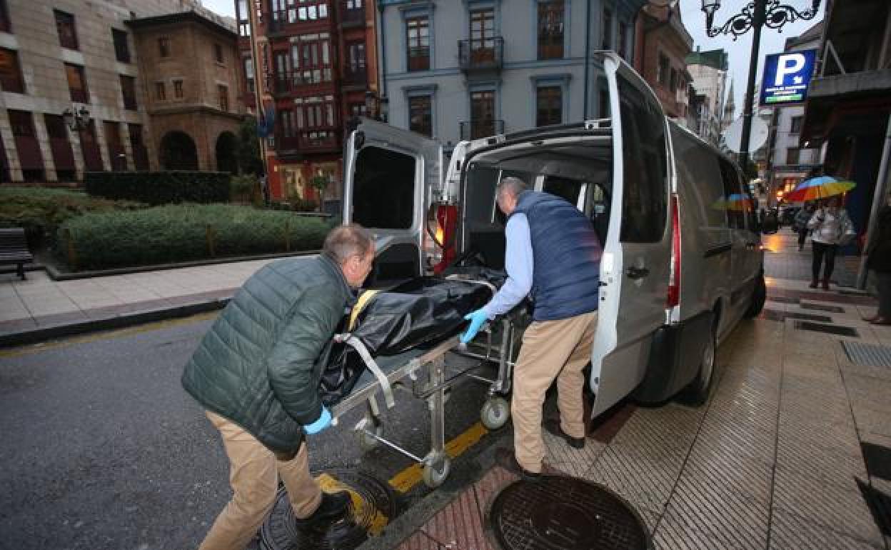 Personal de una funeraria sacan uno de los cuerpos encontrados en un piso de Oviedo.