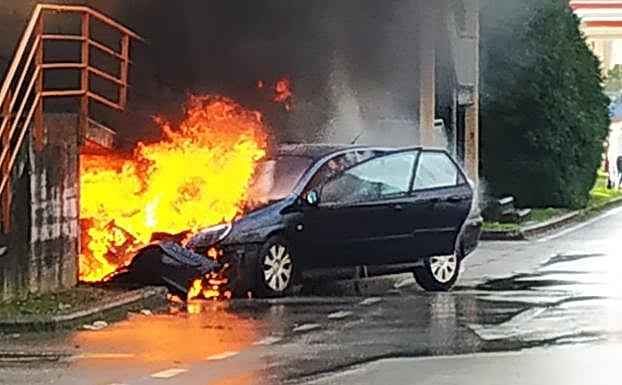 El turismo, envuelto en llamas tras chocar contra un muro. 
