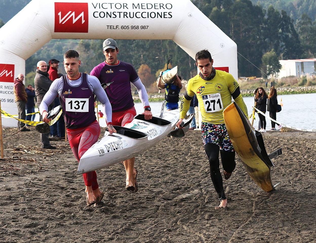 La K-2 de Busto y Geringer, a la izquierda, con el K-1 de Javier López, a la derecha, durante el porteo del Campeonato de Asturias de piragua-cross celebrado ayer en San Juan de la Arena. 