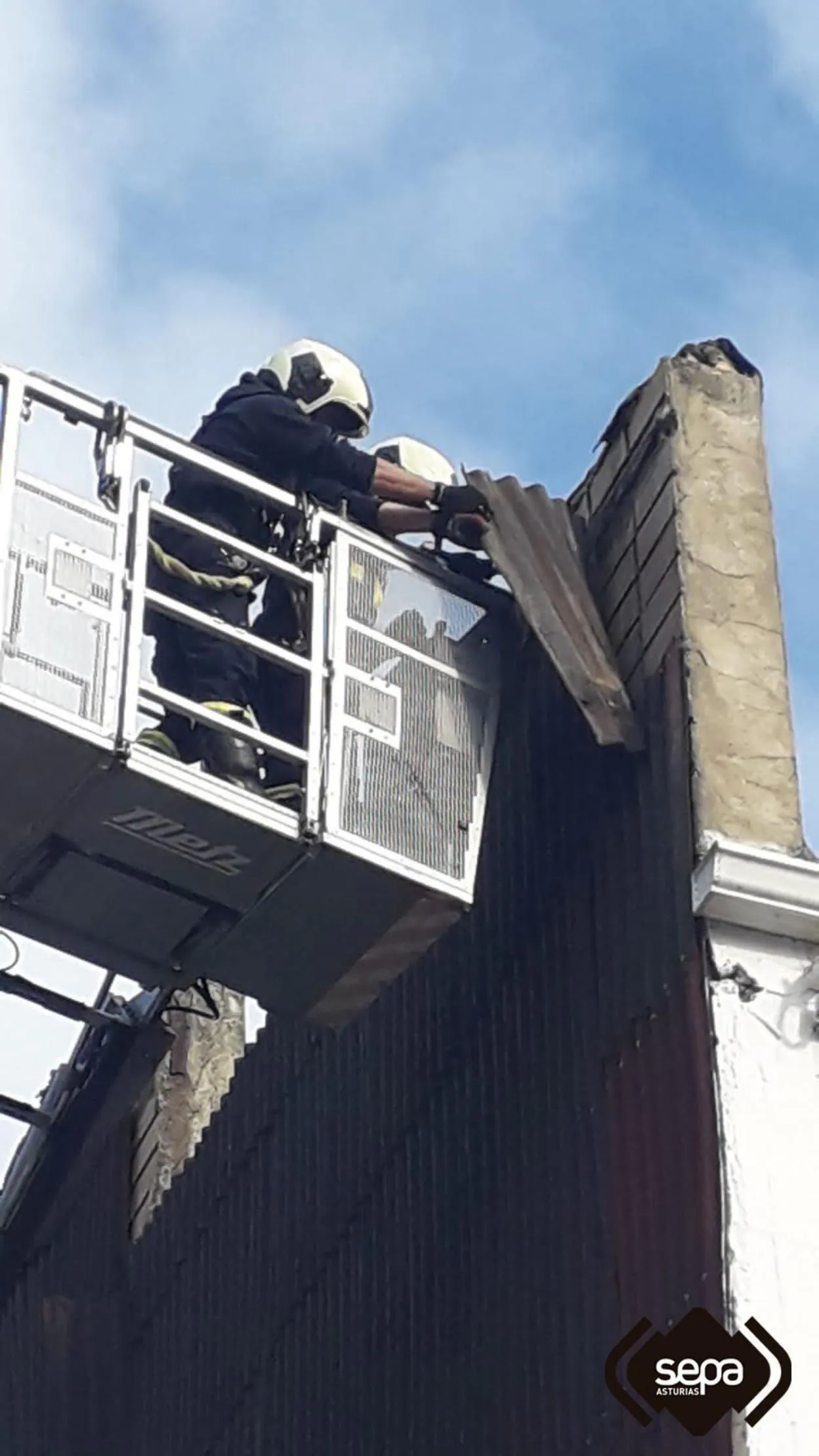 Los bomberos sanean la fachada del edificio en Llanes. :: SEPA