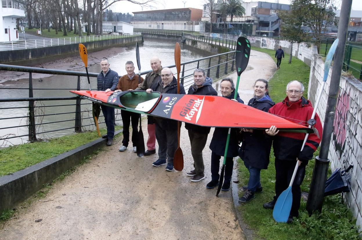 Pepín Viña, Juan Manuel Feliz, Mercurio Martínez, Alberto Estrada, Nemesio Rubio, Luis Tessier, Inmaculada Fidalgo y Manolo García, veteranos del Grupo Covadonga de piragüismo, posan con una canoa delante del anillo del río Piles. 