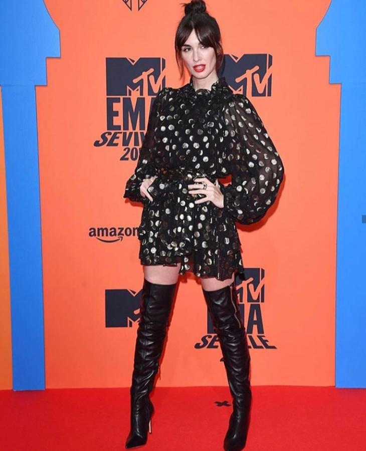 Paz Vega (43 años) con minivestido con mangas abullonadas en color negro y botas altas.