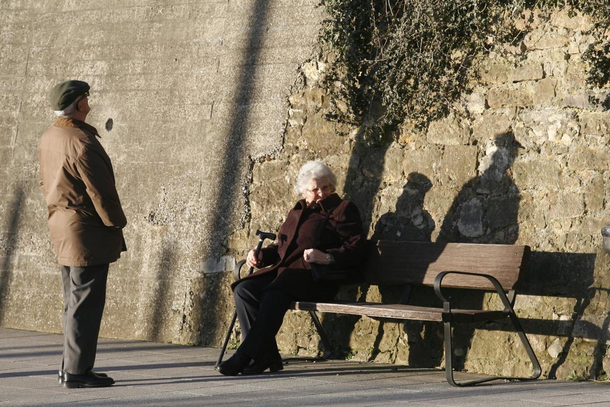 Una pareja de personas mayores disfruta del sol de otoño mientras descansa en un parque ovetense. 