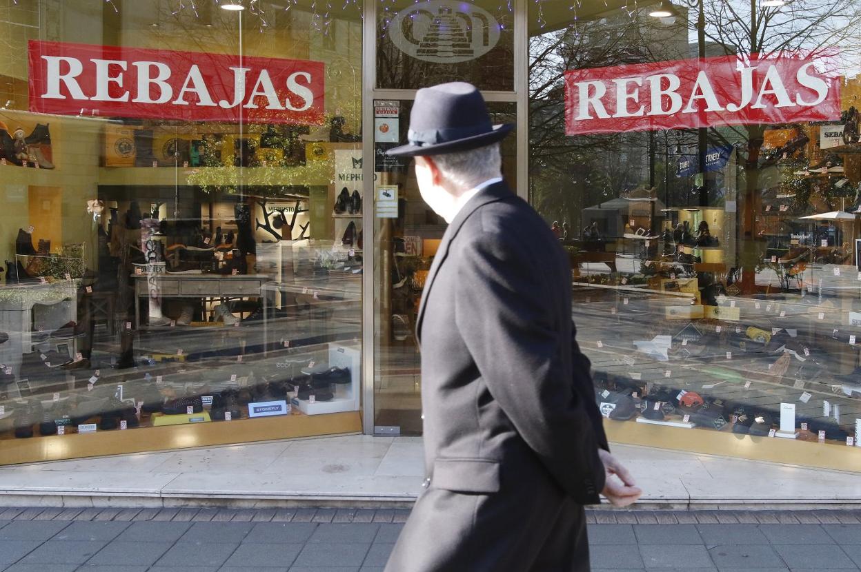 Un hombre observa, en el paseo de Begoña, el escaparate de una zapatería donde ya se anuncian las rebajas. 