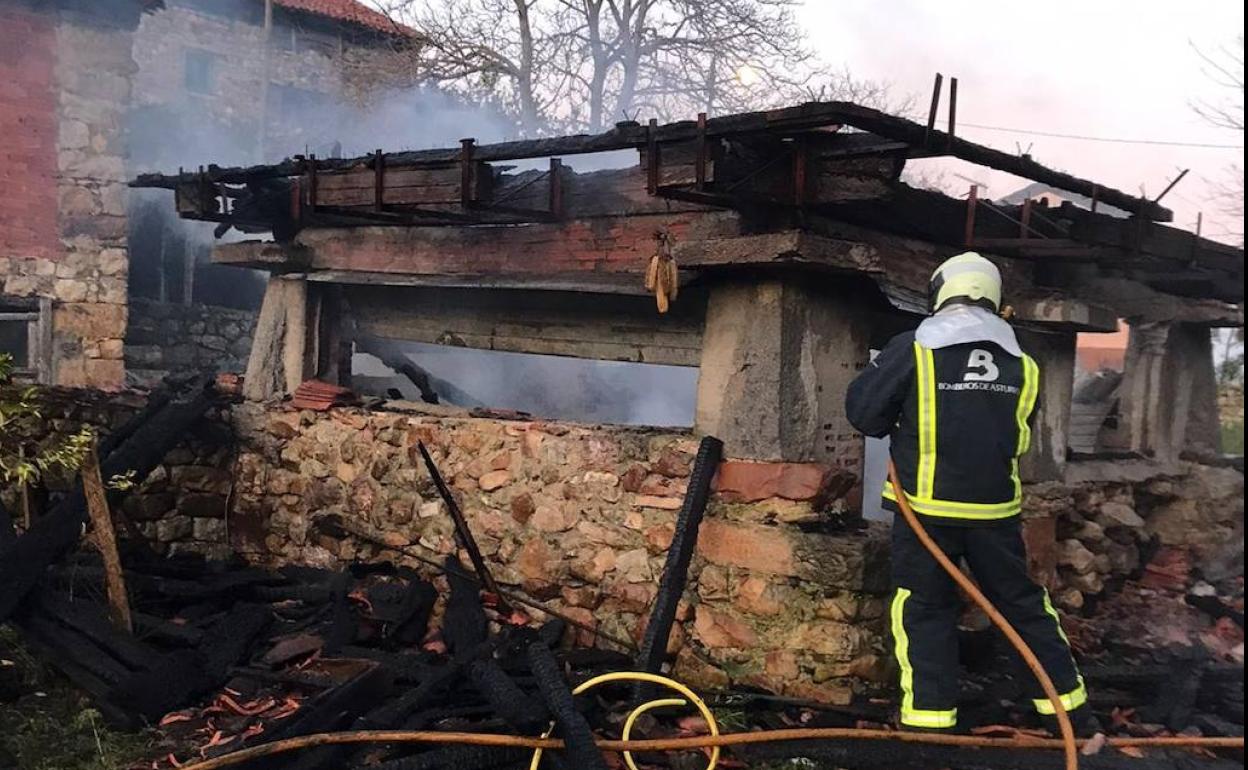 Un bombero trabaja en lo que queda del hórreo.