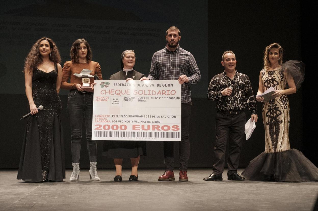 Adrián Arias entrega a María Angustias Illana el cheque solidario en el escenario del Teatro Jovellanos. 