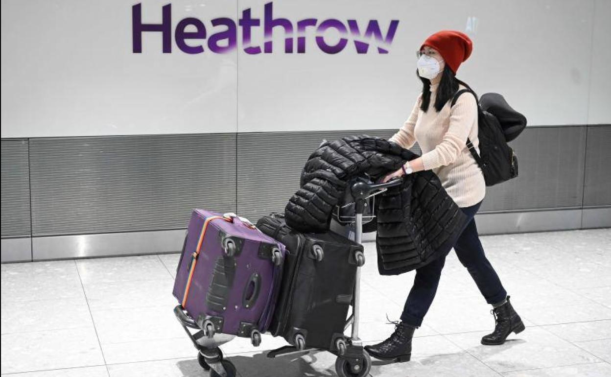 Una pasajera, con mascarilla, en el aeropuerto de Heathrow. 