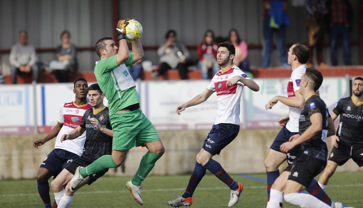 Jesús Lastra agarra el balón ante la amenaza de varios futbolistas del Caudal. 