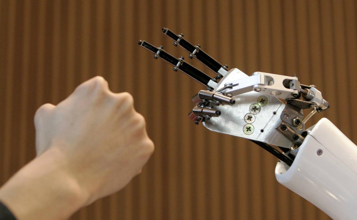 Una persona compara su mano con la de un robot.