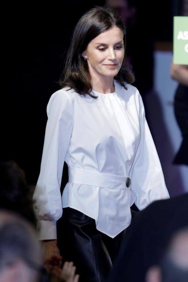Allí la vimos con el perfecto look de oficina formado por una falda evasé de piel en color negro, una blusa blanca de cuello redondo, con mangas ligeramente abullonadas y con un llamativo botón XL que ajustaba la prenda a la altura de la cintura.