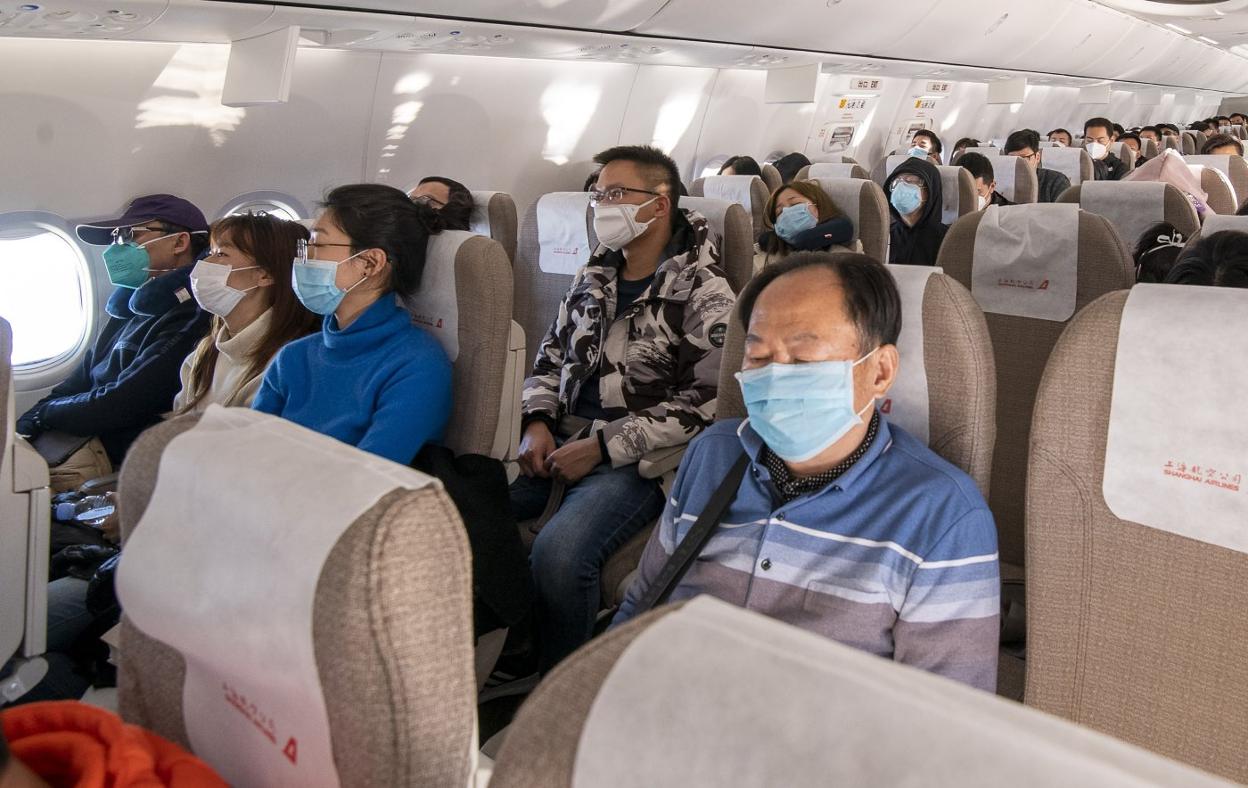 Decenas de viajeros llevan máscaras protectoras a bordo de un avión que se dirige de Jieyang a Shanghai. 