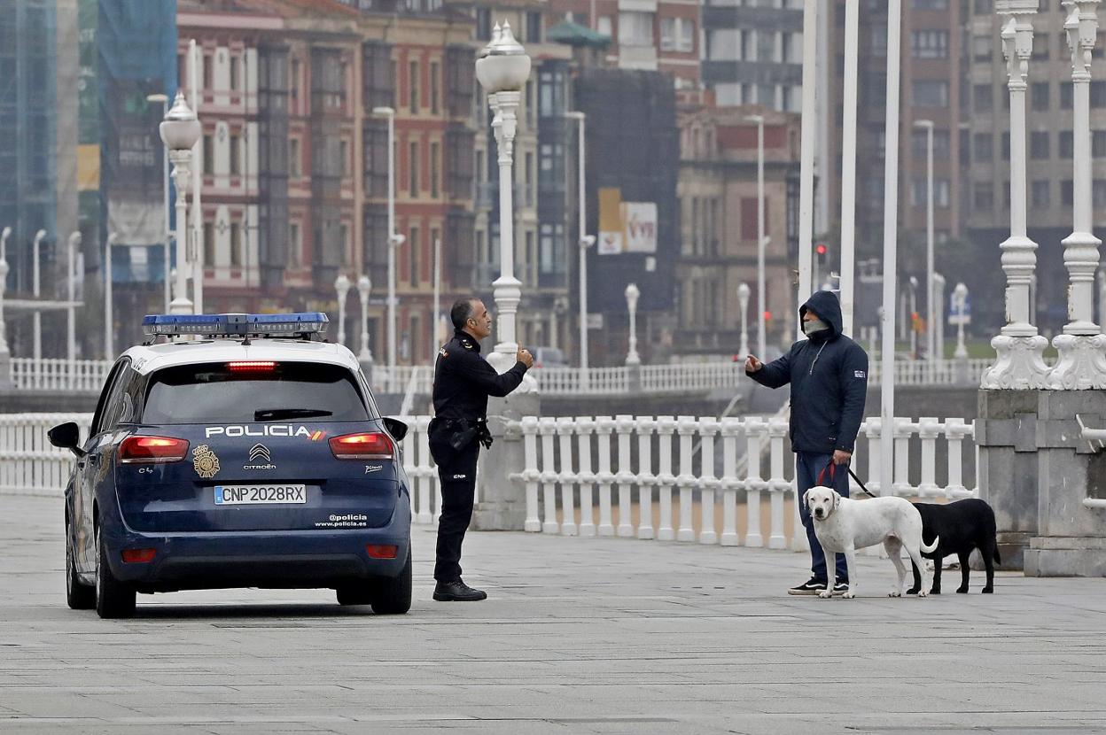 Un policía nacional recrimina a un hombre con dos perros en el paseo del Muro. 