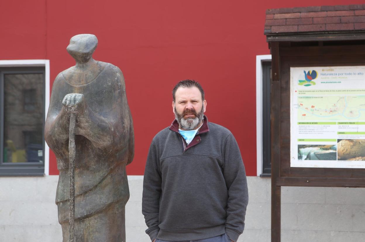José Manuel Abeledo posa junto a la escultura del Pastor, ante el Ayuntamiento de Onís. 