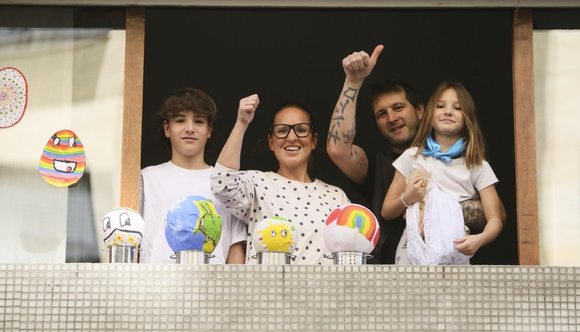 Una familia saludando ayer desde la ventana en la calle Ería del Hospital.