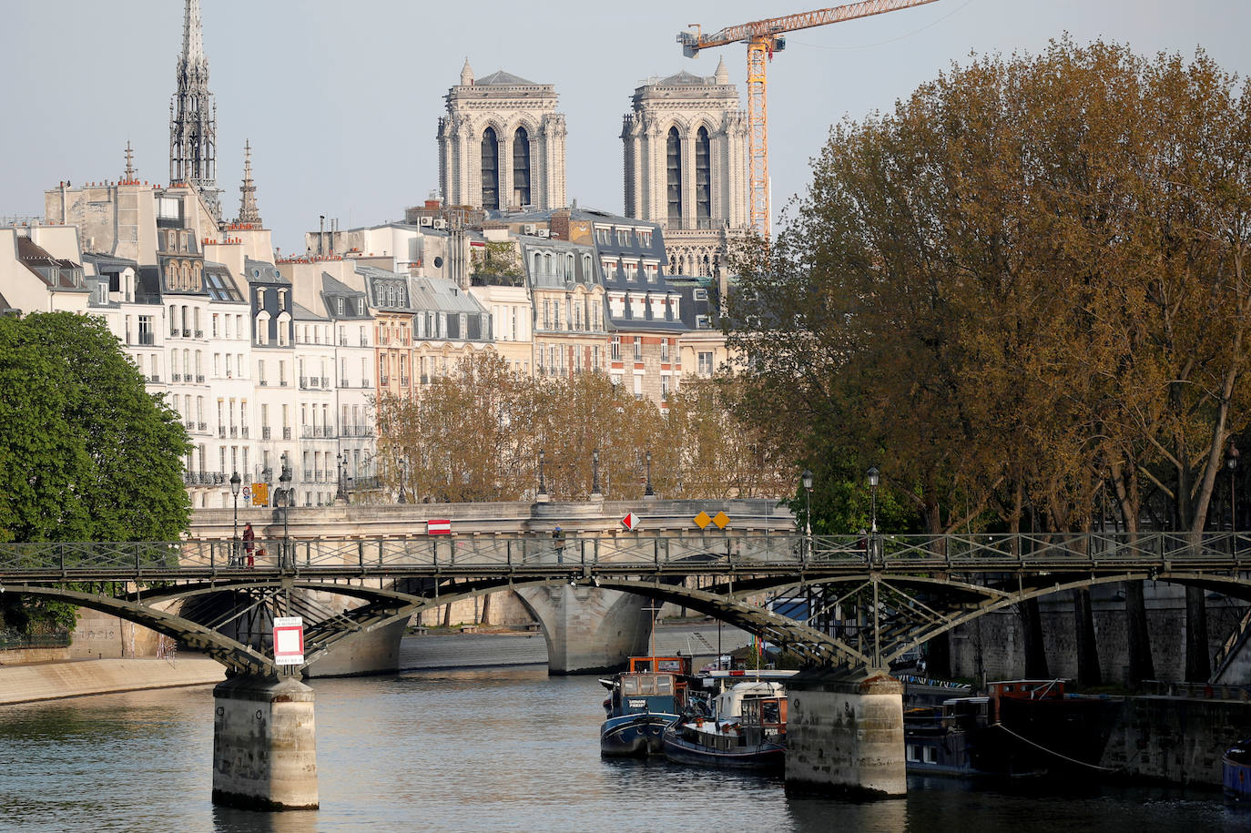 Ocho siglos de historia quedaron en suspenso cuando el 15 de abril de 2019 un incendio derribó la aguja de Notre Dame y su cubierta. Un año después, Francia persiste en su objetivo de reabrir la catedral en 2024, aunque el coronavirus mantenga paralizadas las obras. Las vallas que rodean el templo parisino, la grúa sin movimiento y los andamios que velan por su estructura son reflejo de aquella fatídica tarde, sobre la que la Justicia todavía no ha podido esclarecer el origen de las llamas. El avance de las pesquisas y de la restauración está determinado por la pandemia que ha puesto en hibernación al mundo. Aunque la investigación judicial prosigue en manos de la Brigada Criminal, el análisis técnico se vio frenado cuando este 16 de marzo las obras se suspendieron hasta nueva orden por precaución sanitaria.