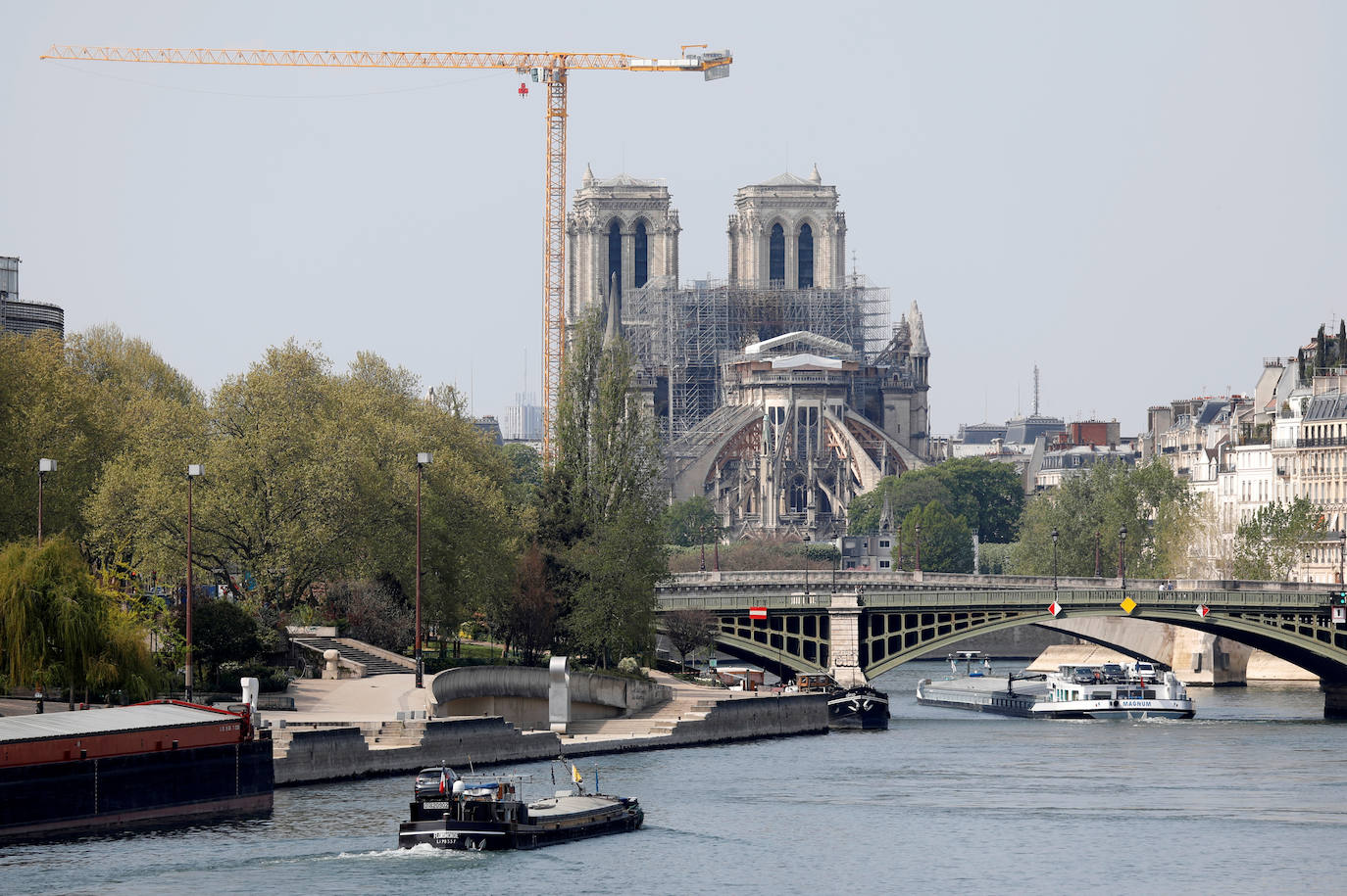 Ocho siglos de historia quedaron en suspenso cuando el 15 de abril de 2019 un incendio derribó la aguja de Notre Dame y su cubierta. Un año después, Francia persiste en su objetivo de reabrir la catedral en 2024, aunque el coronavirus mantenga paralizadas las obras. Las vallas que rodean el templo parisino, la grúa sin movimiento y los andamios que velan por su estructura son reflejo de aquella fatídica tarde, sobre la que la Justicia todavía no ha podido esclarecer el origen de las llamas. El avance de las pesquisas y de la restauración está determinado por la pandemia que ha puesto en hibernación al mundo. Aunque la investigación judicial prosigue en manos de la Brigada Criminal, el análisis técnico se vio frenado cuando este 16 de marzo las obras se suspendieron hasta nueva orden por precaución sanitaria.