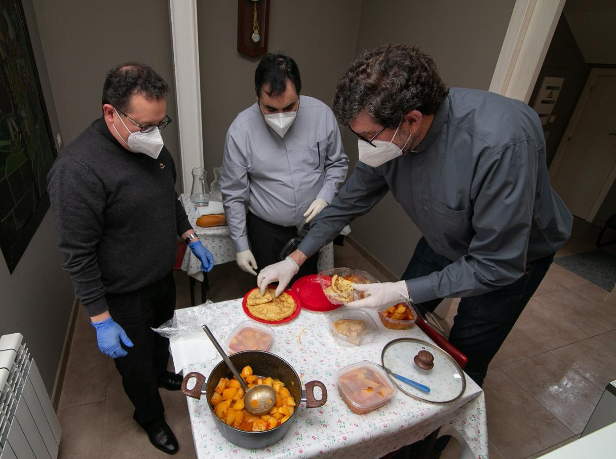 Juan Hevia, Sergio Santa y Andrés Fernández emplatan la comida para servirla a las personas sin hogar de Pola de Siero. 