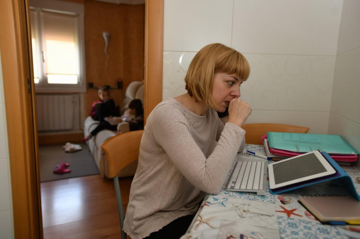 Una madre teletrabaja mientras sus hijos hacen los deberes. 