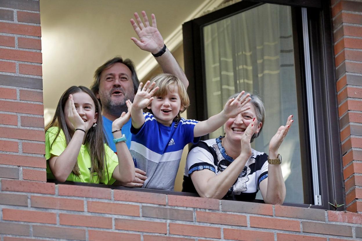 Una familia gijonesa aplaude desde su vivienda de la calle Corín Tellado, de Viesques. 