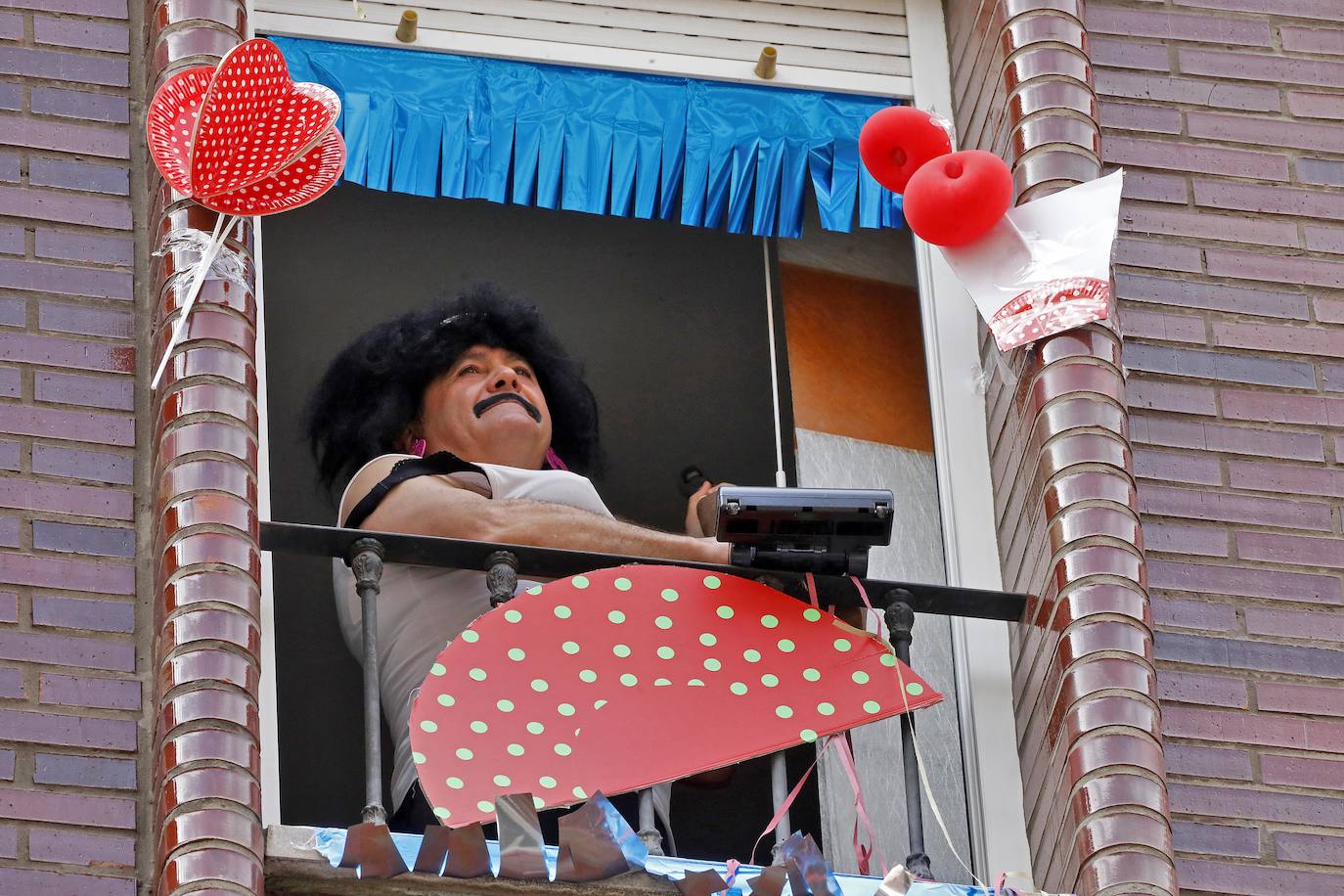 Vecinos del barrio de Contrueces se divierten este domingo desde sus ventanas emulando la estética del videoclip de Queen 'I want to break free'. 