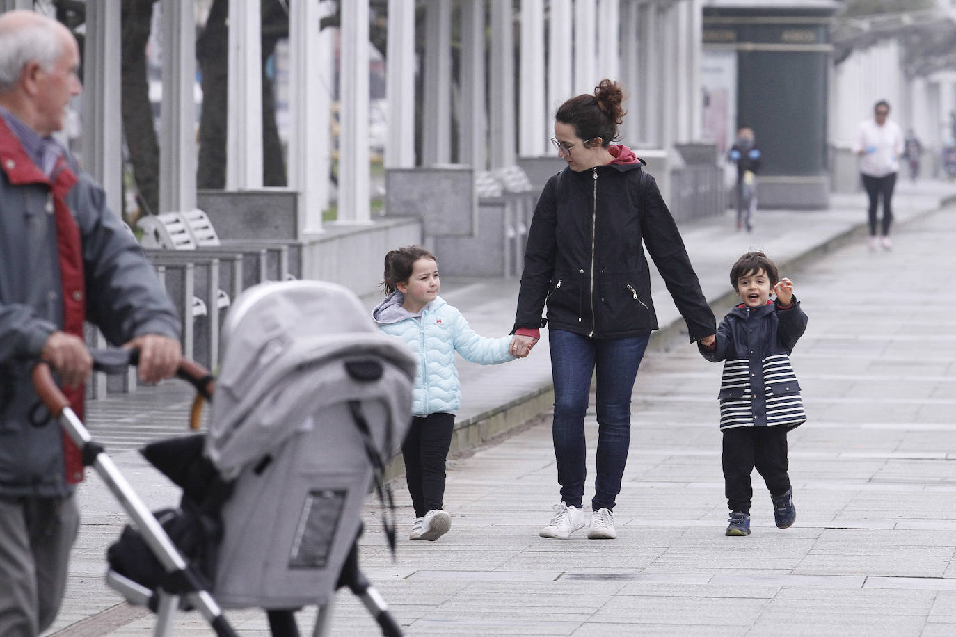 Primeros paseos bajo el orbayu en Gijón de los más pequeños