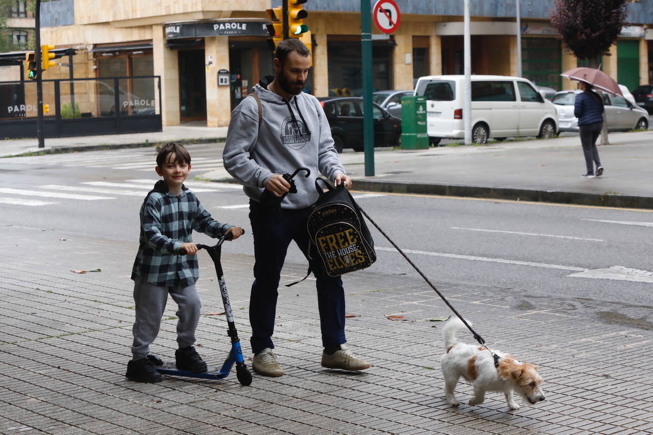 Primeros paseos bajo el orbayu en Gijón de los más pequeños