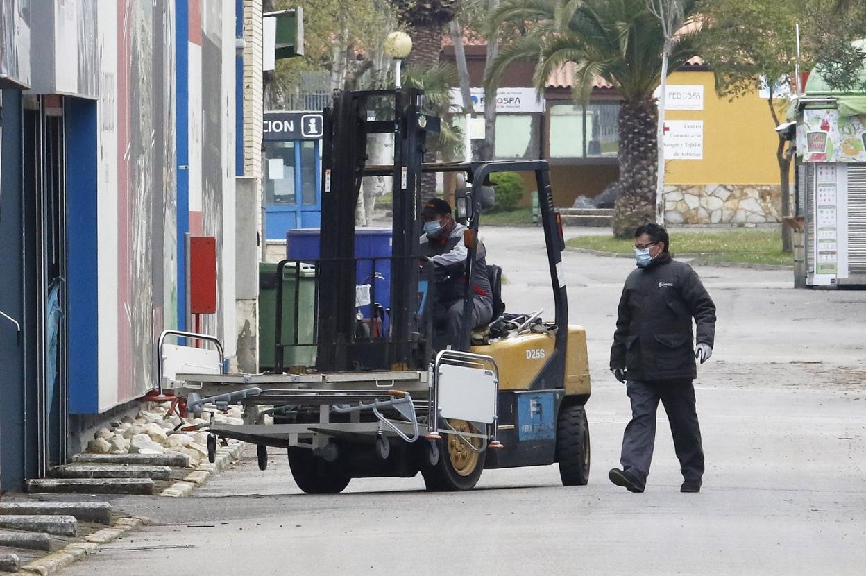Dos operarios introducen una de las camas del hospital provisional en el pabellón. 