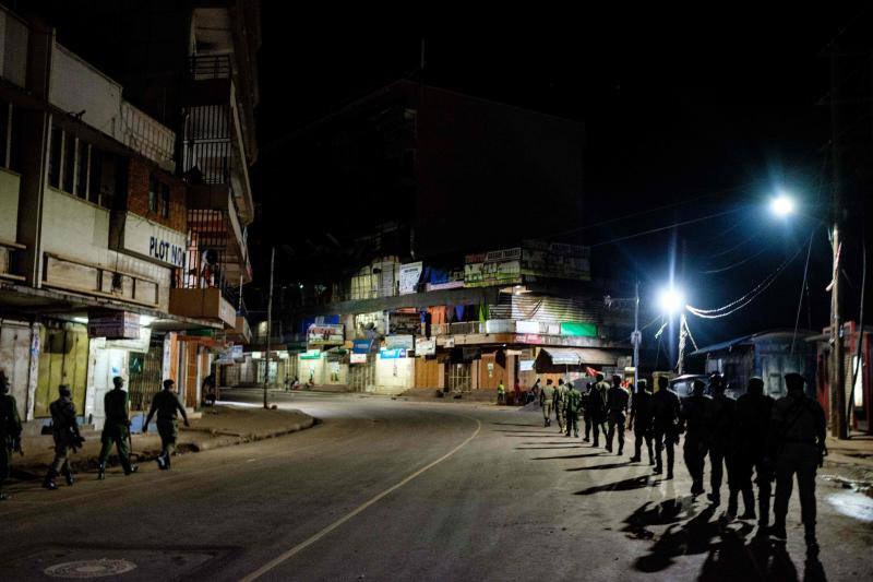 Varios policías ugandeses y miembros de una fuerza paramilitar compuesta por civiles patrullan por las noches en la ciudad de Kampala para asegurarse del cumplimiento del toque de queda nocturno decretado el 14 de abril en Uganda para tratar de detener la propagación del coronavirus. 