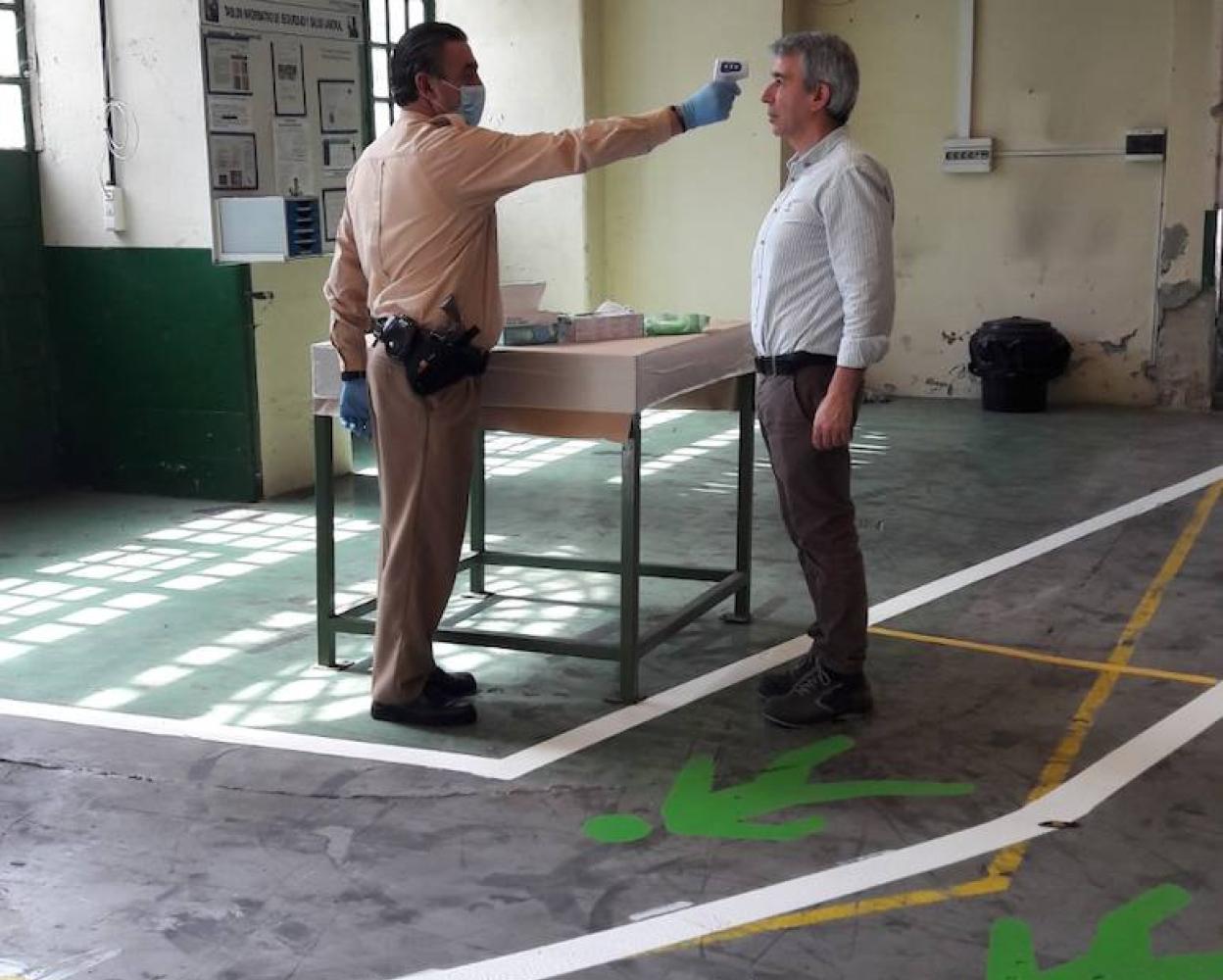 El personal de seguridad realiza controles de temperatura para permitir el acceso a la factoría.