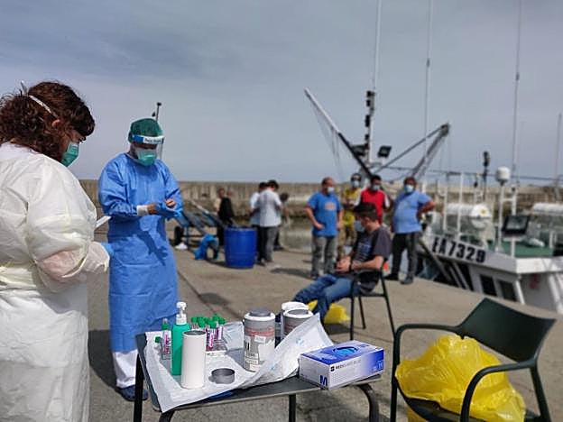Los sanitarios realizan los test a los tripulantes de dos embarcaciones en el puerto de Cudillero. 