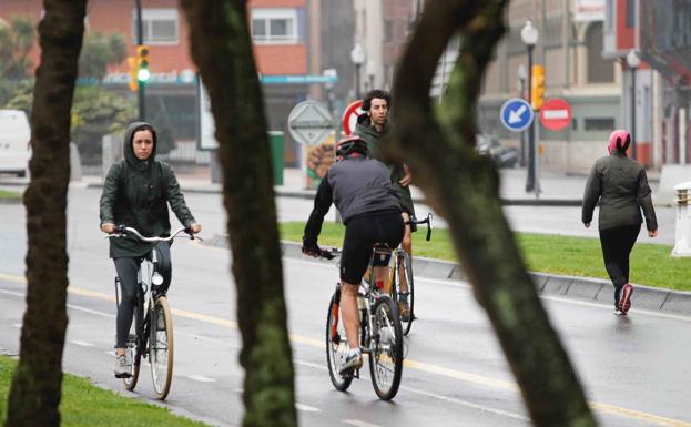 Un grupo de ciclistas en el paseo de El Muro de Gijón. 