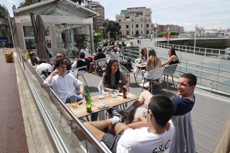 Tras ocho semanas con las verjas bajadas y las sillas y mesas apiladas, los establecimientos hosteleros de Gijón han vuelto a colocar sus terrazas. Eso sí, bajo estrictas medidas de higiene y aforo para prevenir el contagio de coronavirus. 