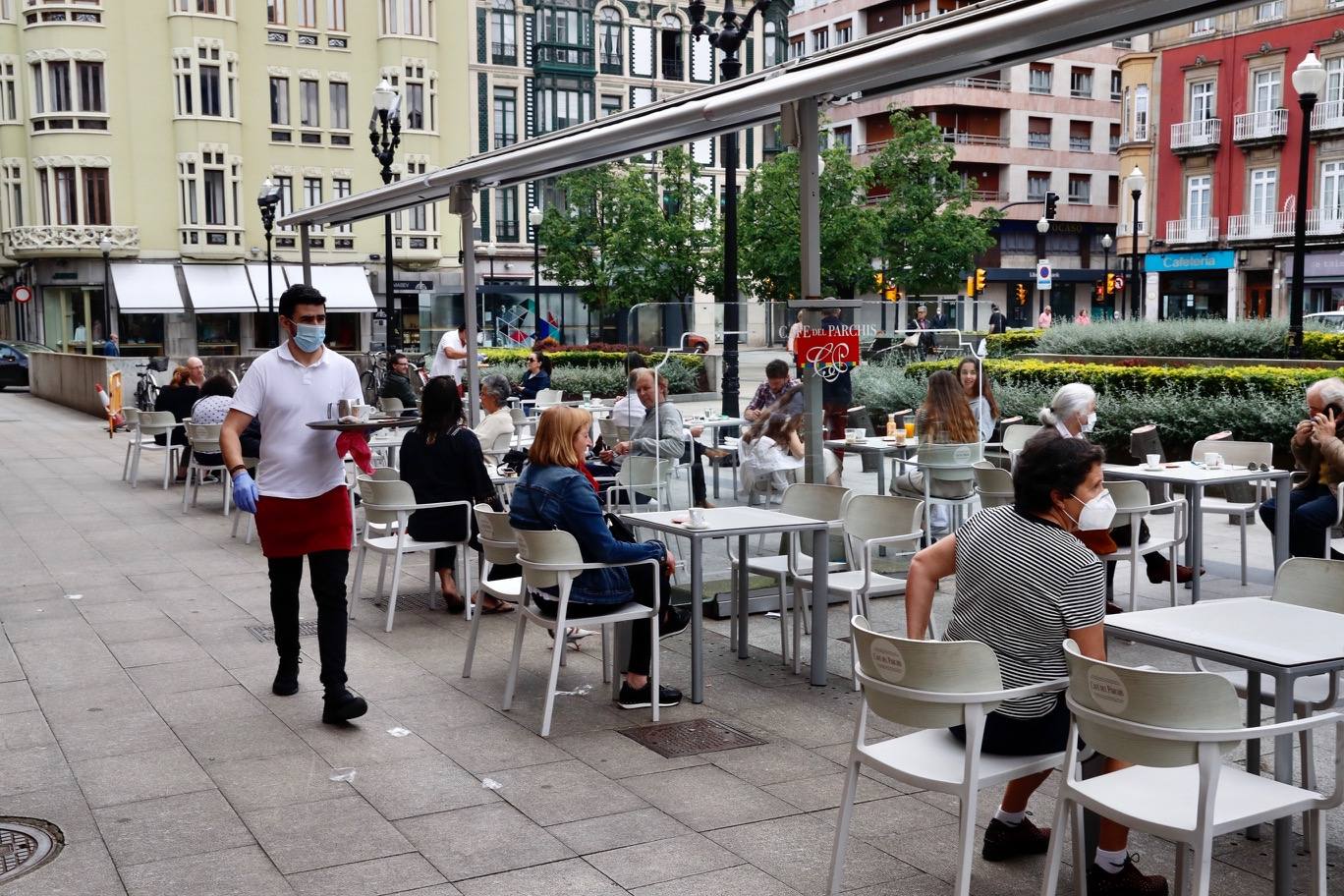 Por primera vez desde que se declaró el estado de alarma por la pandemia de coronavirus los asturianos han podido acudir a las terrazas de bares y cafeterías. Este lunes ha comenzado la fase 1 de la desescalada en el Principado y una de las medidas de alivio del confinamiento es la apertura de terrazas, aunque los establecimientos hosteleros deben acatar estrictas medidas de precaución, como la limpieza exhaustiva de las sillas y mesas o la limitación de aforo. 