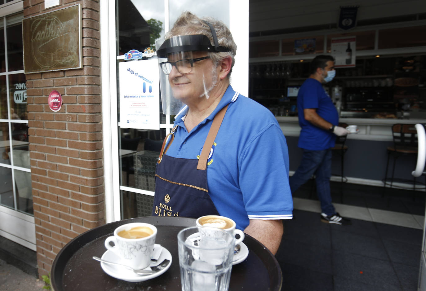 Por primera vez desde que se declaró el estado de alarma por la pandemia de coronavirus los asturianos han podido acudir a las terrazas de bares y cafeterías. Este lunes ha comenzado la fase 1 de la desescalada en el Principado y una de las medidas de alivio del confinamiento es la apertura de terrazas, aunque los establecimientos hosteleros deben acatar estrictas medidas de precaución, como la limpieza exhaustiva de las sillas y mesas o la limitación de aforo. 