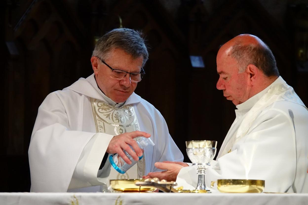 El abad Adolfo Mariño desinfecta las manos de un sacerdote. 