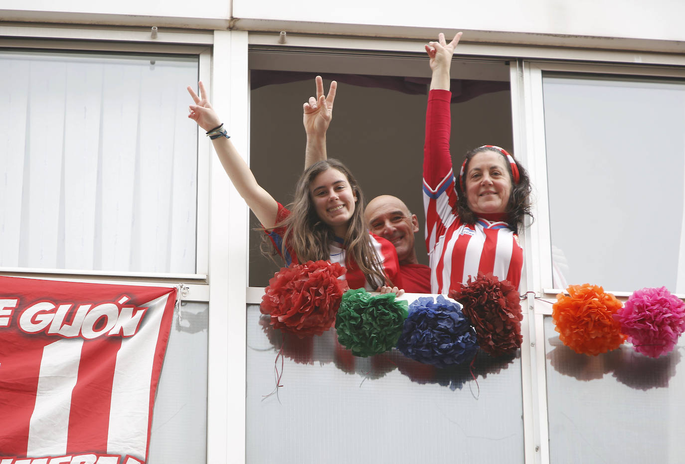 29 de marzo. Gijón | Personas confinadas en sus domicilios por el decreto de alarma celebran el vermú del domingo en ventanas y balcones. 