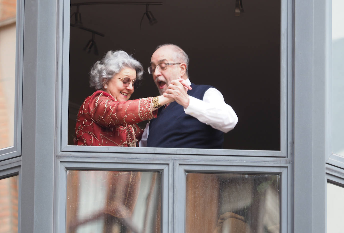 05 de abril. Gijón | Una pareja baila en la ventada de su casa 'un domingo cualquiera' de confinamiento. 
