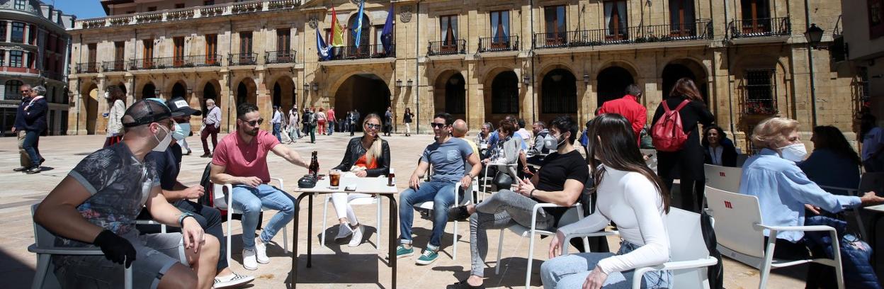 Siete jóvenes en una terraza de la plaza del Ayuntamiento. 