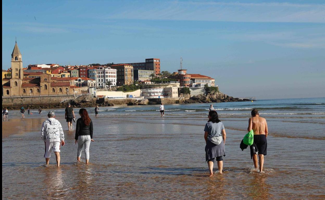 Un grupo de personas, paseando este lunes por la playa de Gijón