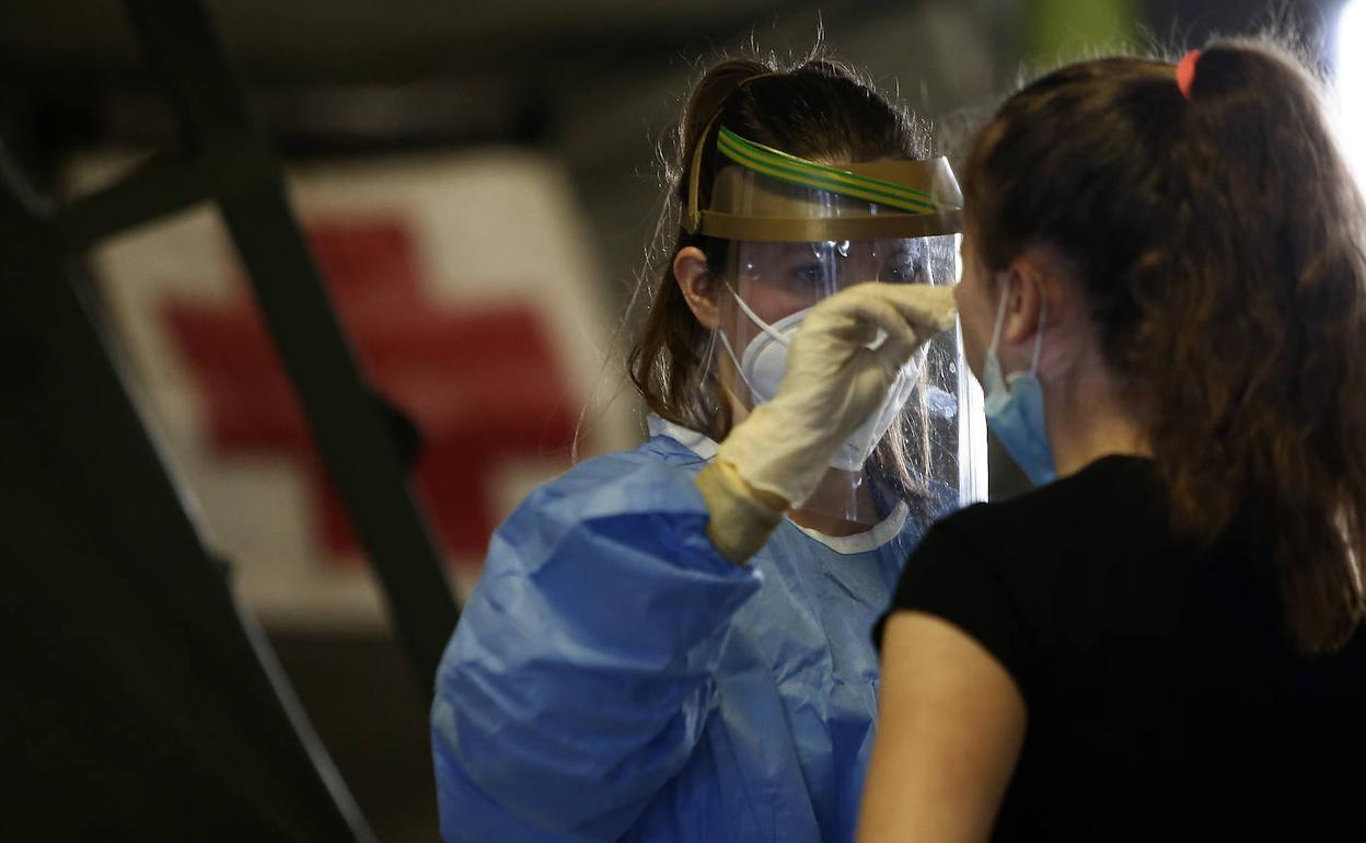 Una sanitaria realiza el test del coronavirus a una mujer en el Hospital de Campaña del párking del HUCA. 