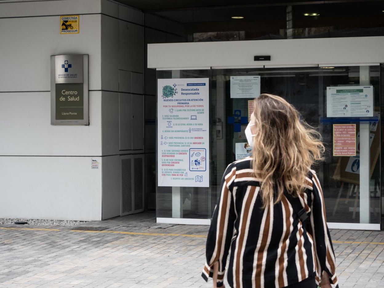 Una paciente llega al centro de salud de Llano Ponte, donde un cartel informa de las nuevas normas. 