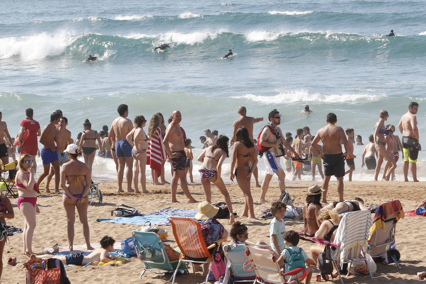 Los arenales gijoneses han vuelto este martes a llenarse de gente que ha querido pasar una nueva jornada de intenso calor tumbado en la arena o refrescándose en el agua.